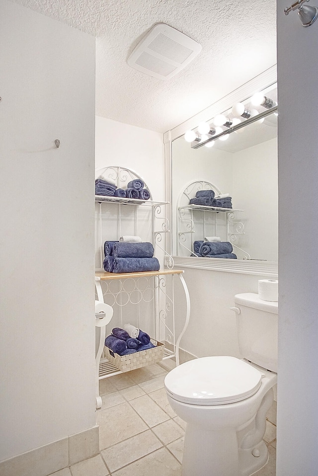 bathroom featuring toilet, tile patterned flooring, visible vents, and a textured ceiling