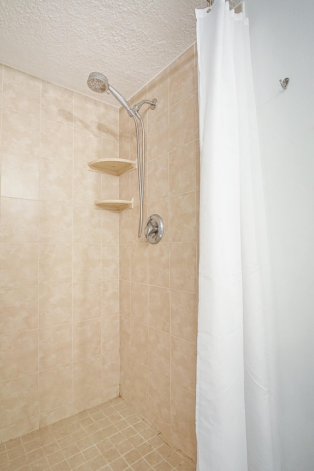 full bath with a tile shower and a textured ceiling