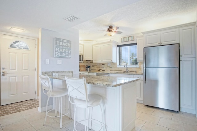 kitchen featuring appliances with stainless steel finishes, tasteful backsplash, ceiling fan, and light tile floors