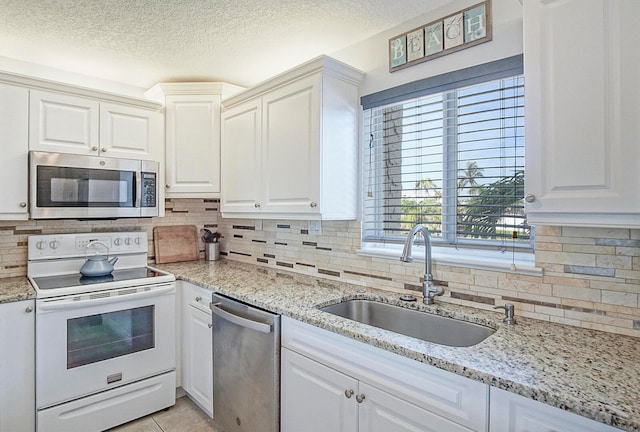 kitchen with light tile patterned floors, a sink, stainless steel appliances, a textured ceiling, and backsplash