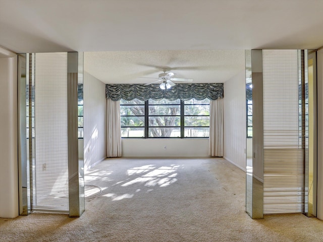 carpeted empty room with ceiling fan and a textured ceiling