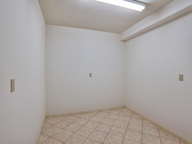 spare room featuring light tile floors and a textured ceiling