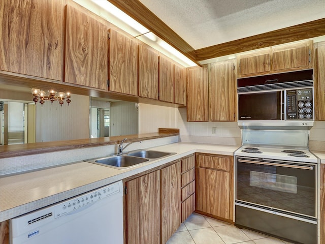 kitchen featuring light tile floors, a textured ceiling, sink, white appliances, and a notable chandelier