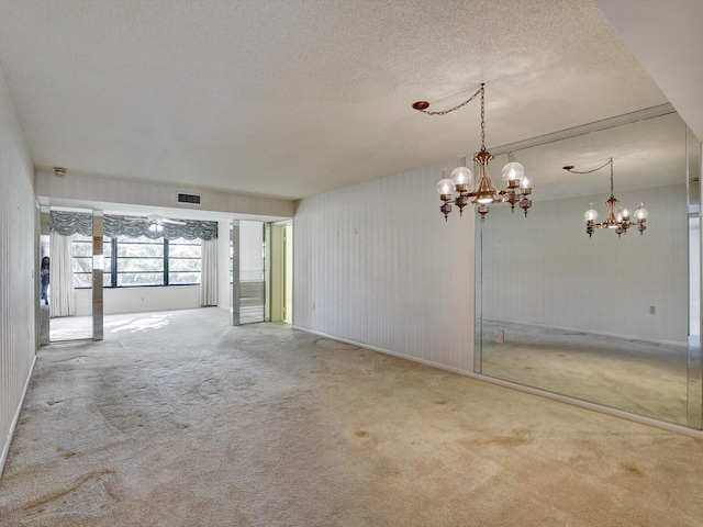 unfurnished room with an inviting chandelier, carpet flooring, and a textured ceiling