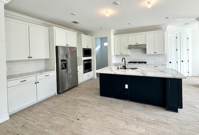 kitchen with white cabinets, a textured ceiling, stainless steel appliances, and a kitchen island with sink