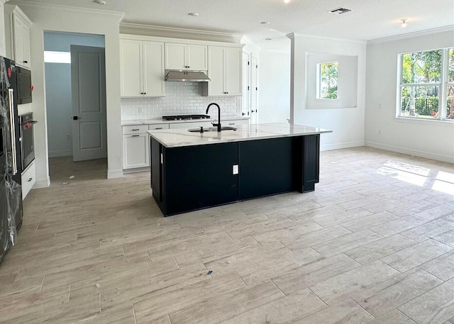 kitchen featuring a center island with sink, oven, white cabinetry, and ornamental molding