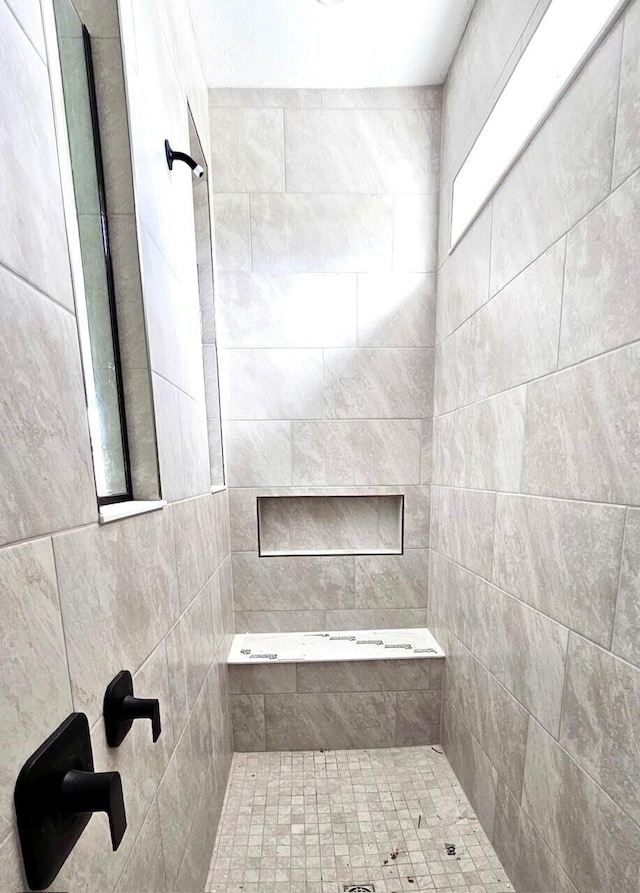 bathroom with a healthy amount of sunlight and tiled shower