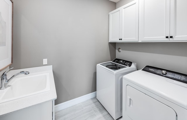 washroom with cabinets, washing machine and dryer, and sink