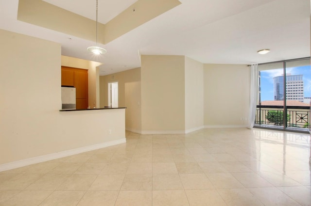 spare room featuring light tile patterned floors, floor to ceiling windows, baseboards, and a view of city