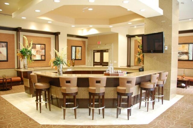 interior space with light tile patterned floors and a raised ceiling