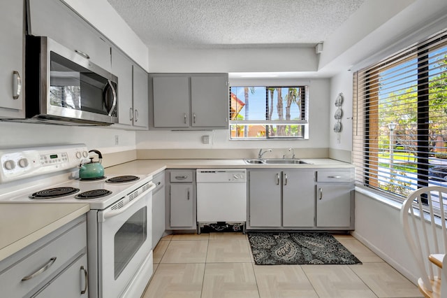 kitchen featuring gray cabinets, a textured ceiling, white appliances, and sink