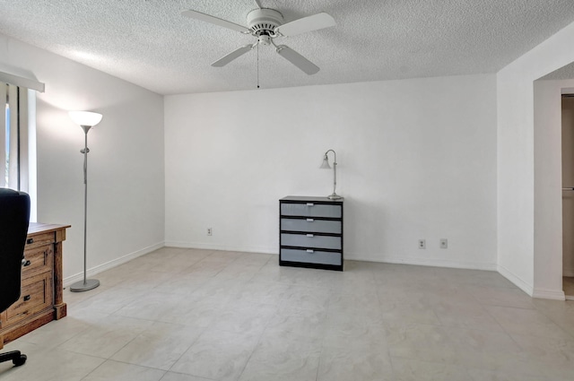 spare room with ceiling fan, light tile floors, and a textured ceiling