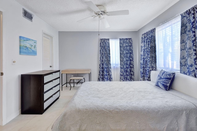 tiled bedroom with a textured ceiling and ceiling fan