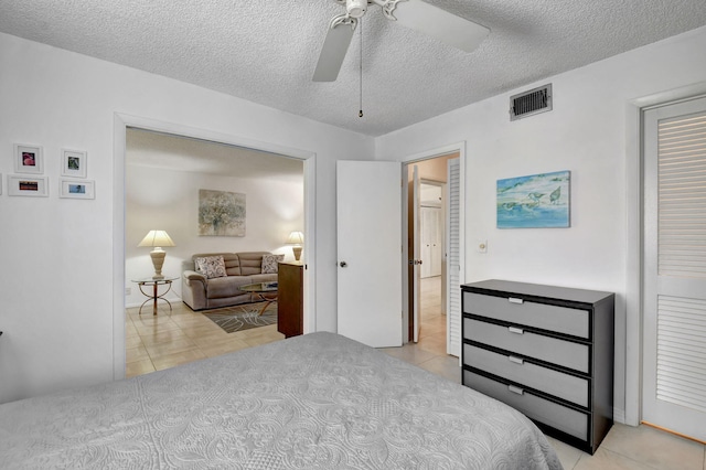 bedroom featuring ceiling fan, a textured ceiling, and light tile flooring