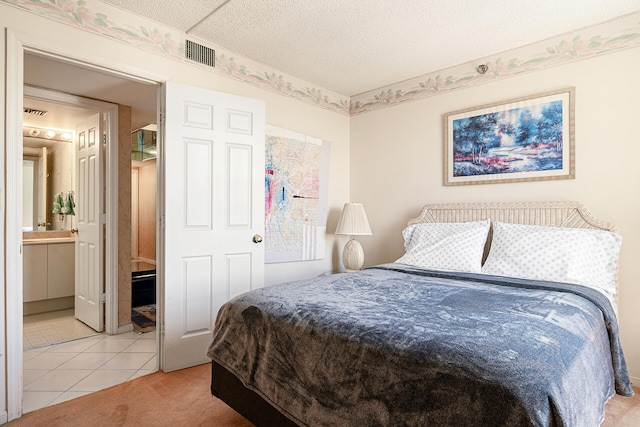 bedroom with a textured ceiling, ensuite bathroom, and light tile floors