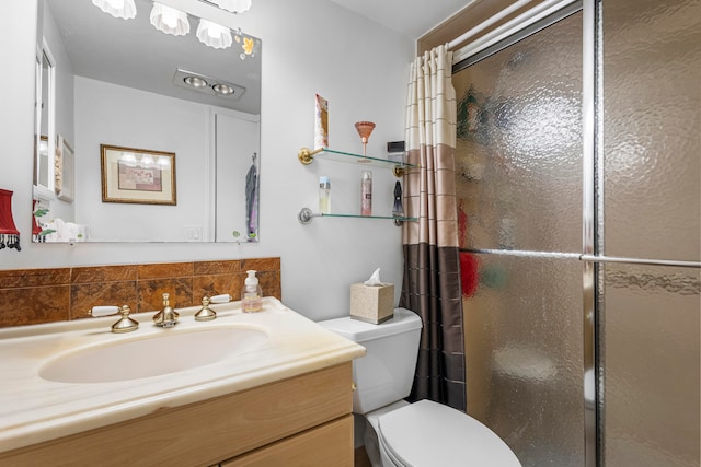 bathroom featuring a shower with shower door, vanity with extensive cabinet space, and toilet