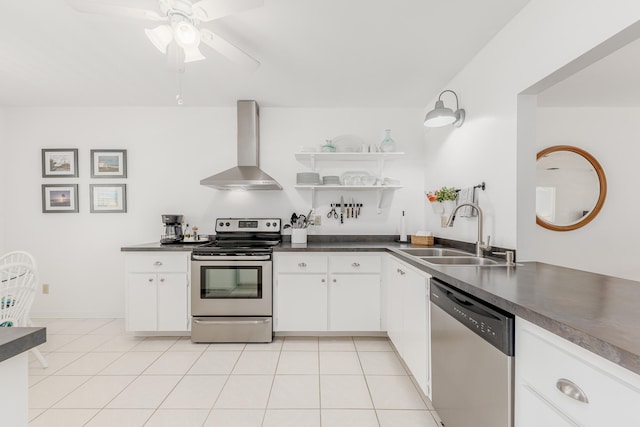 kitchen with appliances with stainless steel finishes, wall chimney range hood, white cabinets, sink, and light tile floors