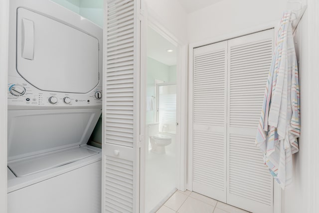 washroom with light tile floors and stacked washing maching and dryer