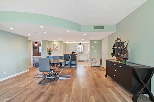 interior space with ceiling fan, a textured ceiling, and light wood-type flooring