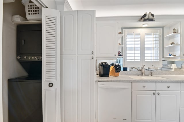 kitchen with stacked washer / drying machine, white cabinetry, dishwasher, and sink