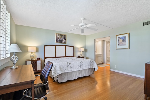 bedroom featuring light wood-type flooring, ceiling fan, connected bathroom, and a textured ceiling