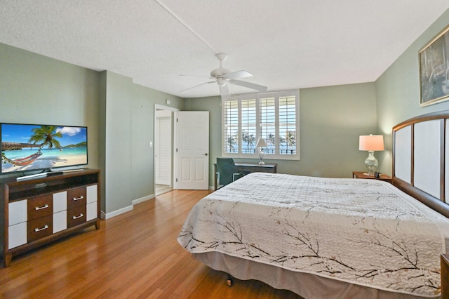 bedroom with a textured ceiling, ceiling fan, and light hardwood / wood-style flooring