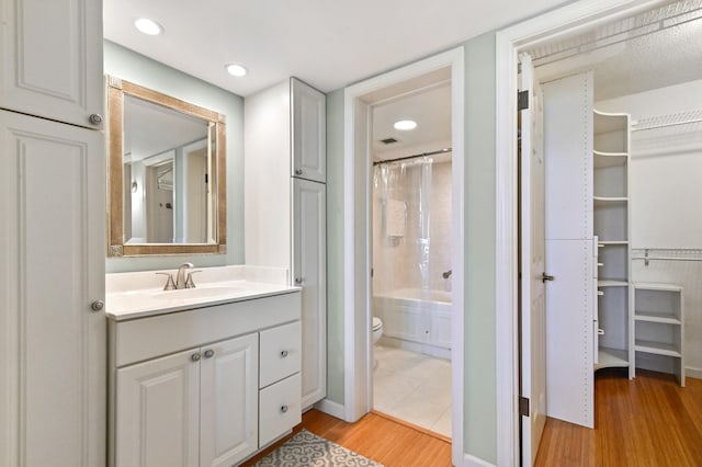 full bathroom with shower / bathtub combination with curtain, hardwood / wood-style flooring, vanity, and toilet