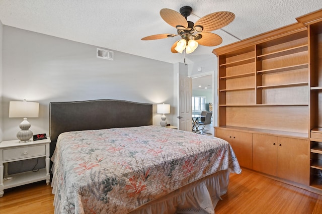 bedroom with ceiling fan, a textured ceiling, and light hardwood / wood-style floors