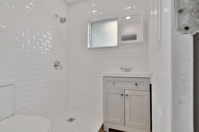 bathroom featuring tile walls, vanity, toilet, and a tile shower