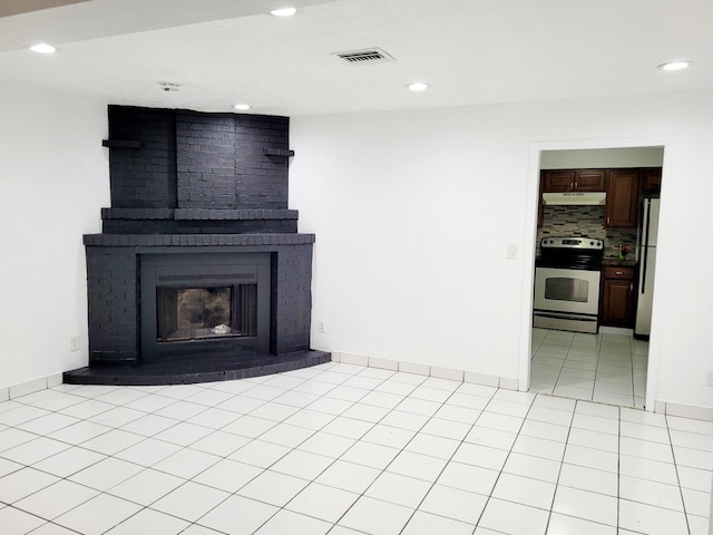 unfurnished living room with a fireplace, brick wall, and light tile floors