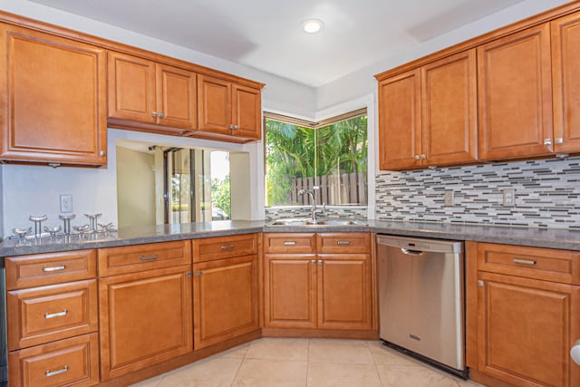 kitchen featuring light tile floors, sink, dishwasher, tasteful backsplash, and dark stone counters