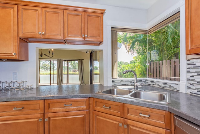 kitchen with a wealth of natural light, tasteful backsplash, dishwasher, and sink