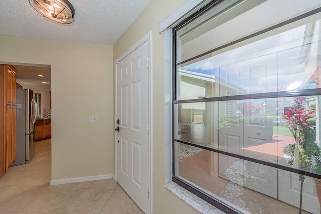 doorway featuring a textured ceiling and light tile flooring