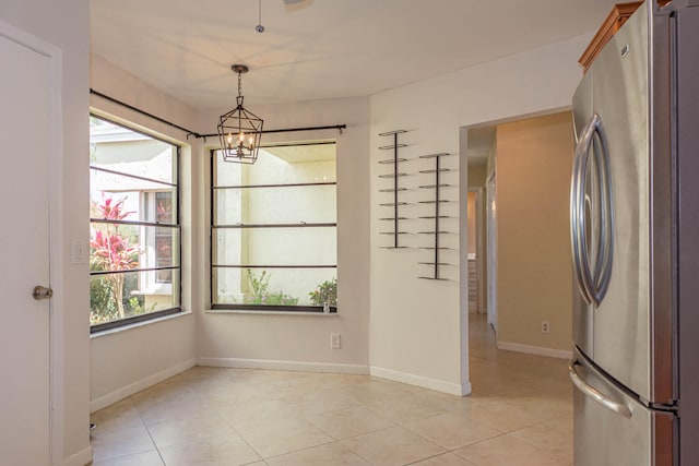 unfurnished dining area featuring an inviting chandelier and light tile floors