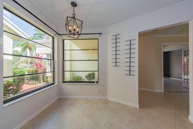 empty room with light tile floors and an inviting chandelier