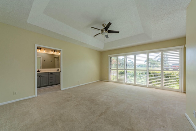 unfurnished room with a textured ceiling, a raised ceiling, ceiling fan, and carpet