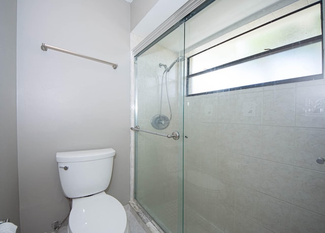 bathroom with a shower with door and toilet