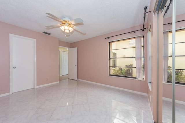 tiled empty room with ceiling fan and a textured ceiling