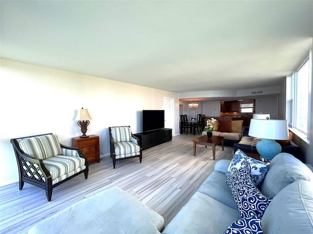 living room with light hardwood / wood-style flooring and a notable chandelier