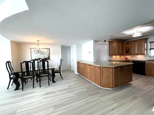 kitchen with light stone countertops, black dishwasher, backsplash, pendant lighting, and a chandelier