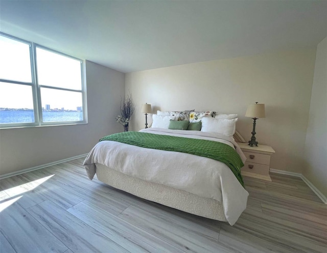 bedroom with a water view and light wood-type flooring