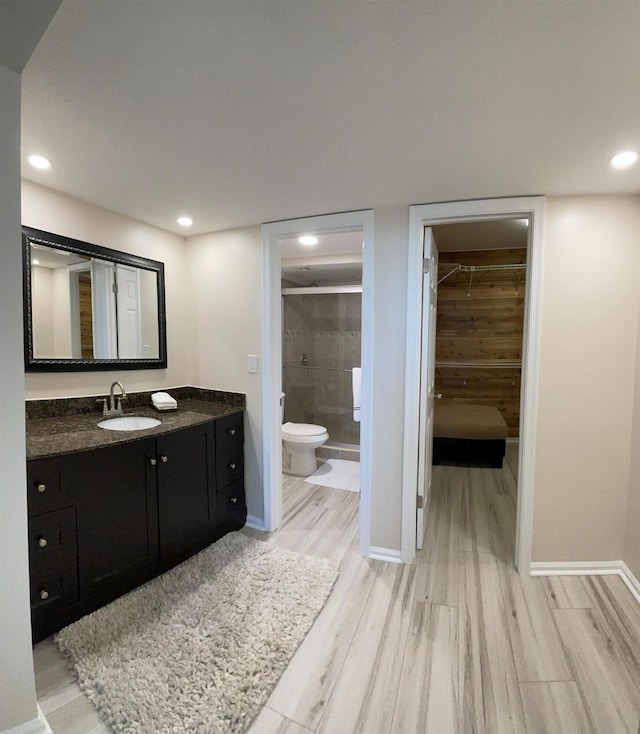 bathroom featuring vanity, toilet, wood-type flooring, and tiled shower