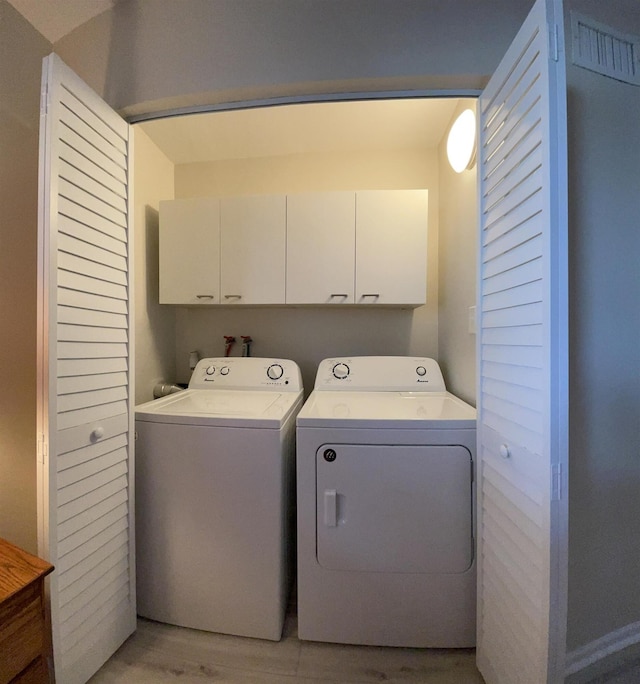 laundry room with cabinets, independent washer and dryer, and light wood-type flooring