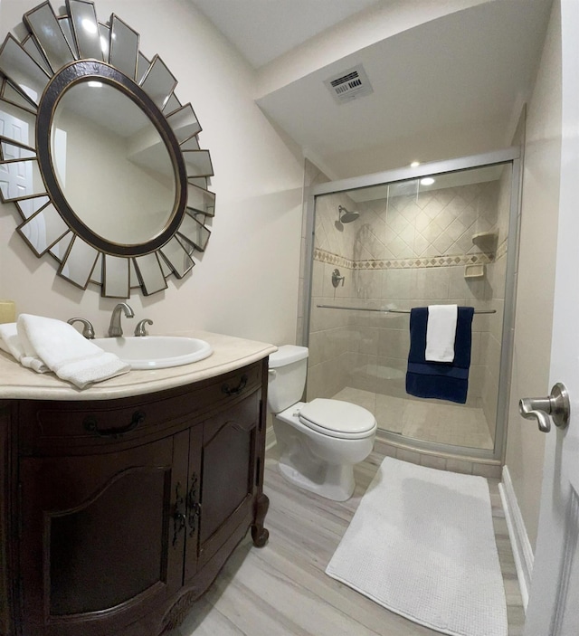 bathroom with toilet, vanity, wood-type flooring, and walk in shower