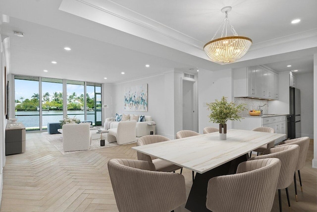 dining room featuring a notable chandelier, light parquet floors, crown molding, and a water view