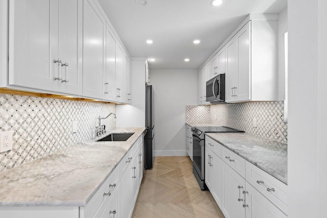 kitchen with tasteful backsplash, stainless steel appliances, light parquet flooring, sink, and white cabinets