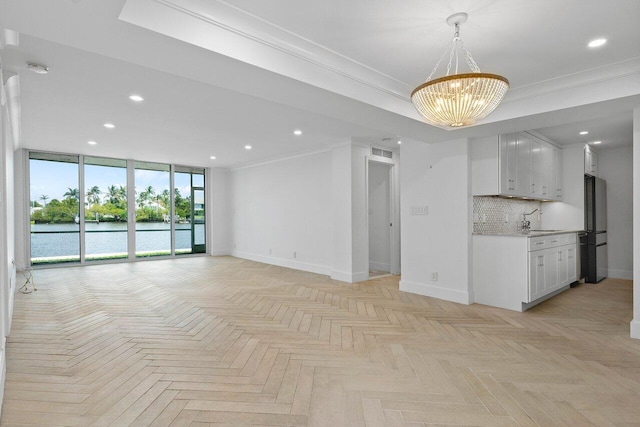 unfurnished living room with crown molding, a water view, light parquet flooring, a chandelier, and sink