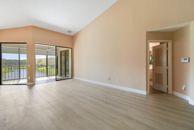 empty room featuring light hardwood / wood-style flooring, a water view, and lofted ceiling