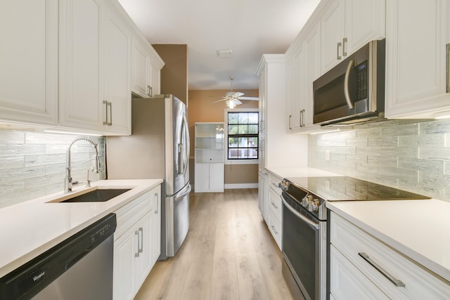 kitchen featuring sink, stainless steel appliances, tasteful backsplash, light hardwood / wood-style flooring, and white cabinets