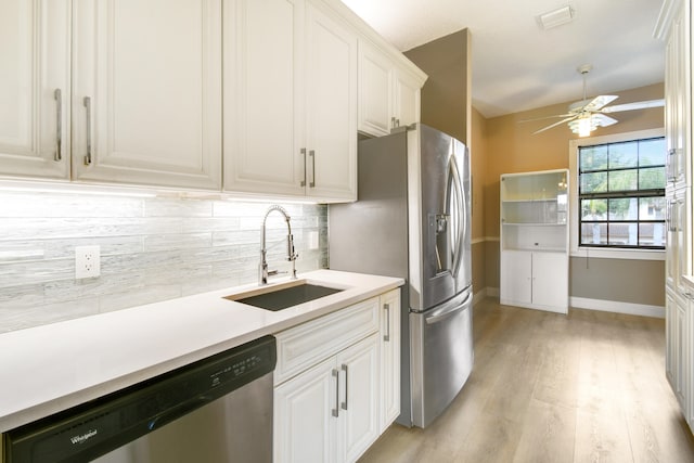 kitchen featuring backsplash, sink, appliances with stainless steel finishes, light hardwood / wood-style floors, and white cabinetry